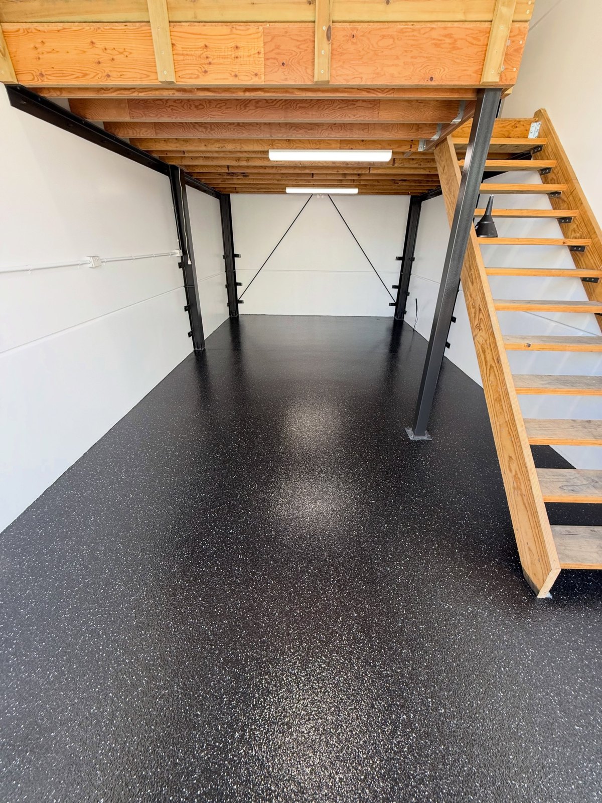 Carbon-black flake workshop floor beneath a timber mezzanine